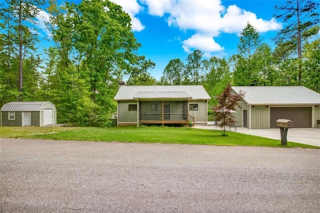 ranch-style home featuring an outbuilding, a detached garage, a front yard, and a storage shed