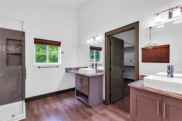 full bathroom featuring wood finished floors, healthy amount of natural light, a chandelier, and a stall shower