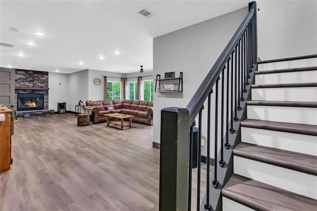 stairway featuring recessed lighting, wood finished floors, a fireplace, and baseboards