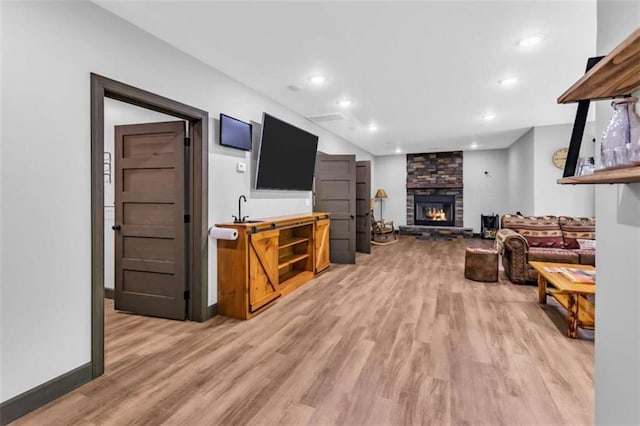 living room with light wood finished floors, a fireplace, recessed lighting, and baseboards