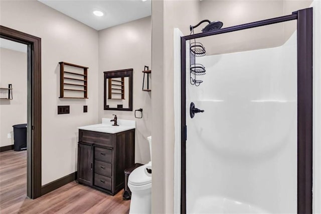 full bathroom featuring wood finished floors, a stall shower, baseboards, and vanity
