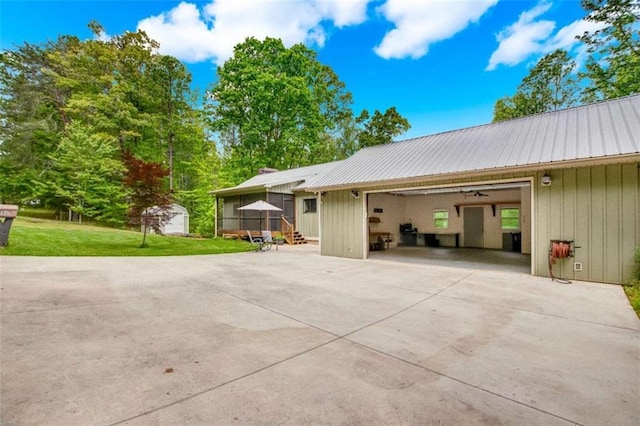 view of side of home featuring metal roof, a lawn, and driveway