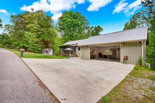 view of side of property with metal roof and driveway