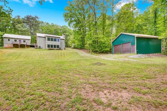 view of green lawn with a detached garage and an outbuilding