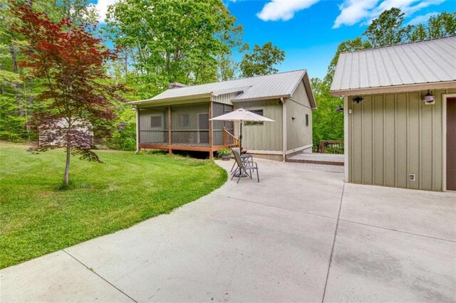 back of property with a patio area, a yard, a sunroom, and metal roof