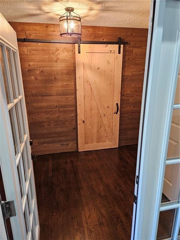 3268 Mae Ave, Brookhaven, GA 30319 - interior space featuring a textured ceiling, wood walls, a barn door, and dark wood-type flooring
