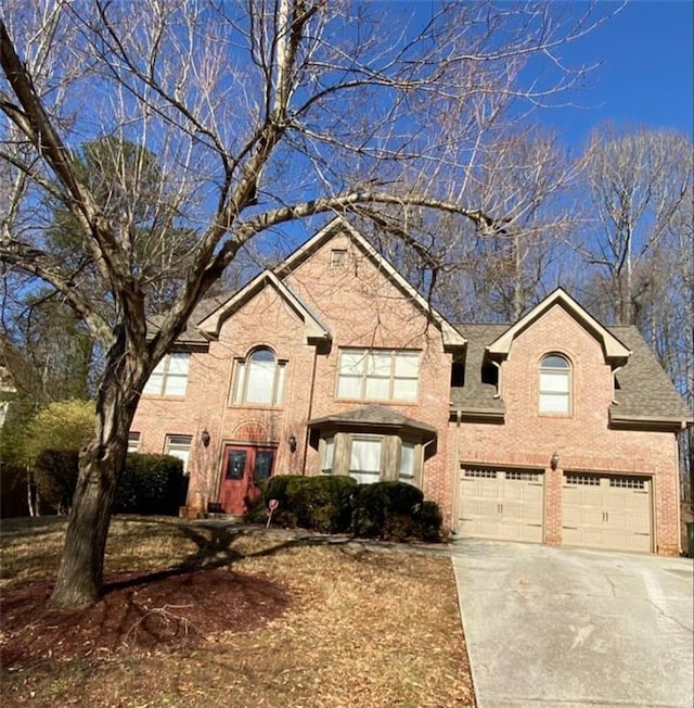 view of front of property featuring a shingled roof, concrete driveway, brick siding, and an attached garage