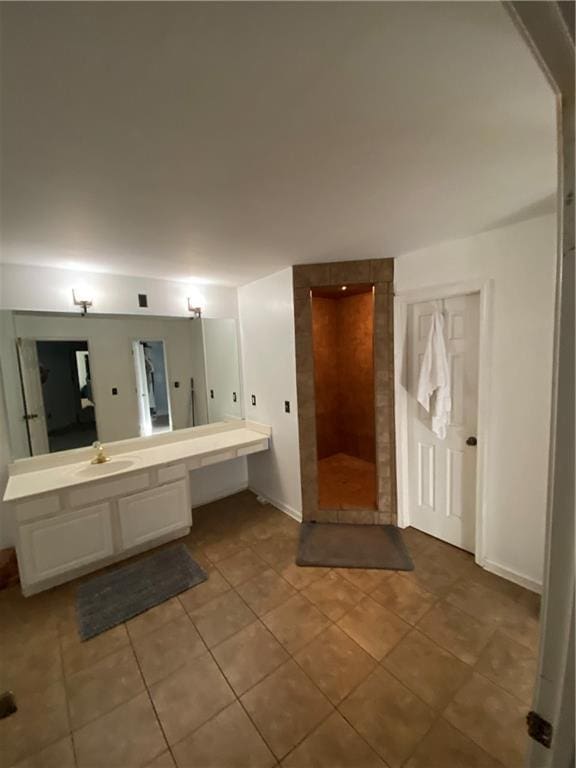 bathroom with walk in shower, tile patterned flooring, vanity, and baseboards