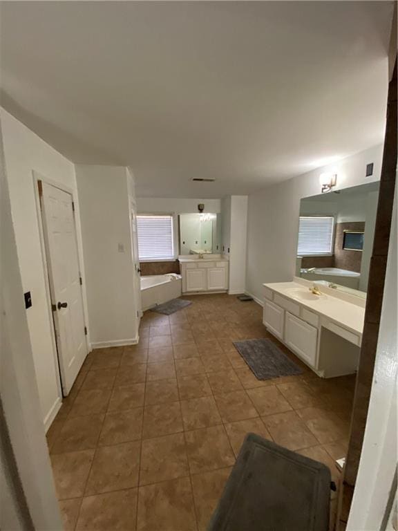 bathroom featuring a garden tub, tile patterned floors, baseboards, and vanity