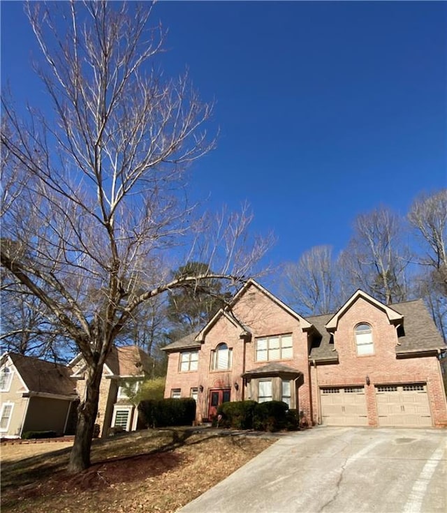 traditional-style home featuring an attached garage, concrete driveway, and brick siding