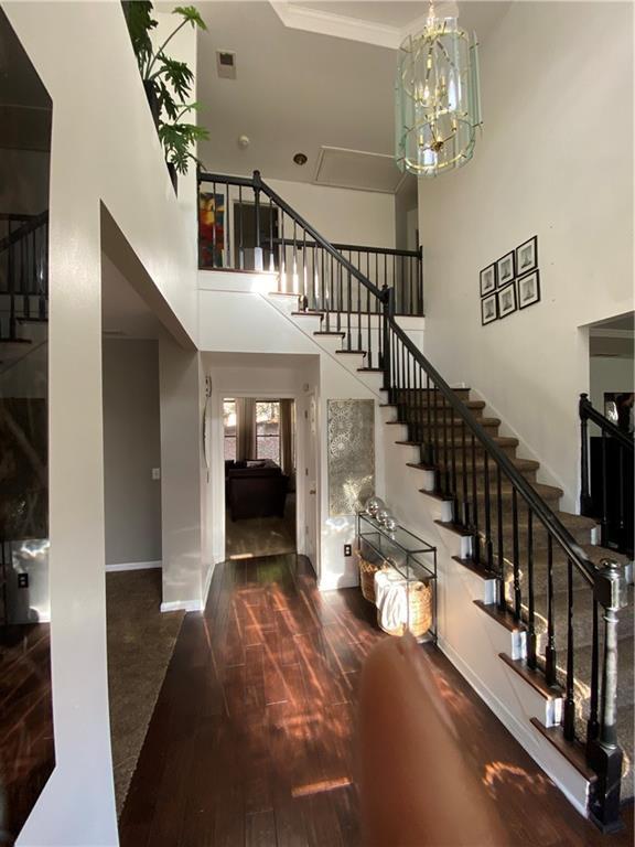 foyer entrance featuring a high ceiling, wood finished floors, baseboards, stairway, and crown molding