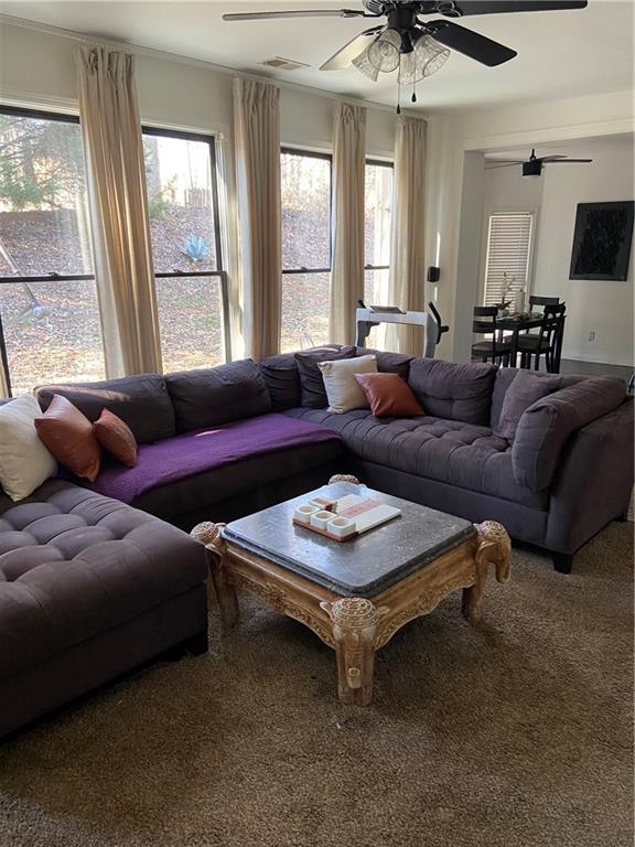 carpeted living area featuring a ceiling fan and visible vents