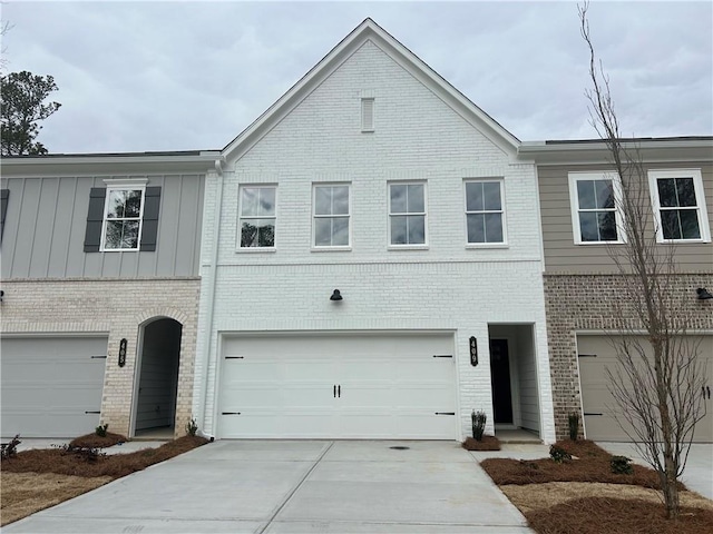 townhome / multi-family property featuring board and batten siding, an attached garage, concrete driveway, and brick siding