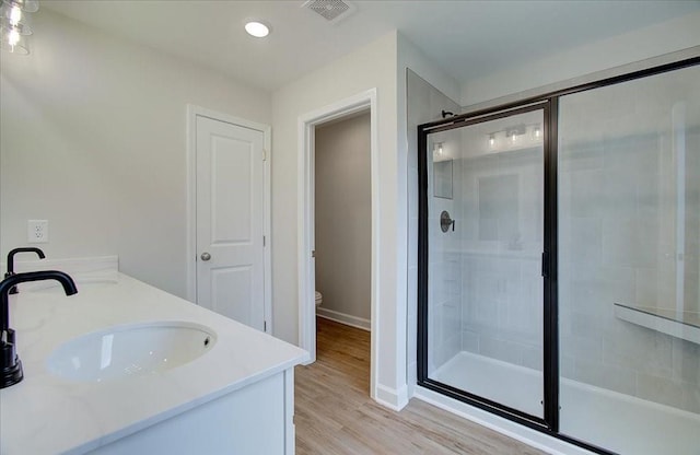 bathroom with a shower with door, wood-type flooring, and vanity