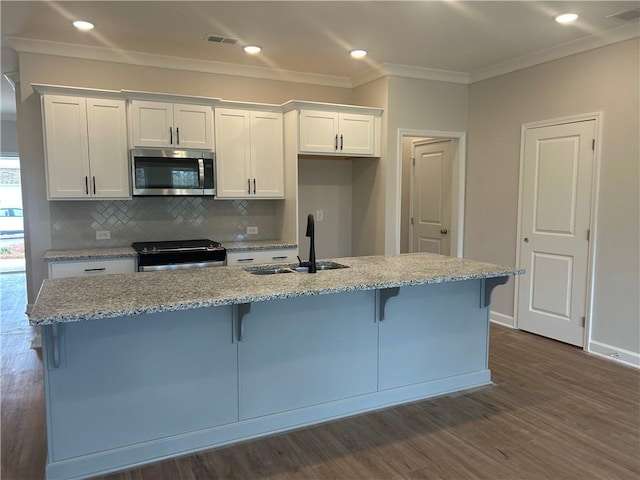 kitchen featuring a kitchen island with sink, appliances with stainless steel finishes, white cabinets, and a sink