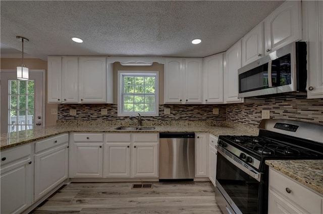 535 Toonigh Rd, Woodstock, GA 30188 - kitchen featuring stainless steel appliances, a sink, a textured ceiling, light wood-style flooring, and light stone countertops