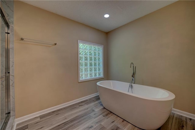 535 Toonigh Rd, Woodstock, GA 30188 - bathroom with wood finished floors, a shower stall, a freestanding tub, baseboards, and a textured ceiling