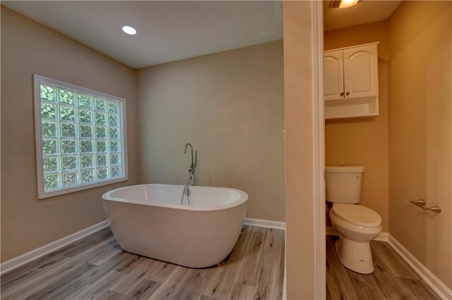 535 Toonigh Rd, Woodstock, GA 30188 - full bath featuring wood finished floors, toilet, a soaking tub, baseboards, and a textured ceiling