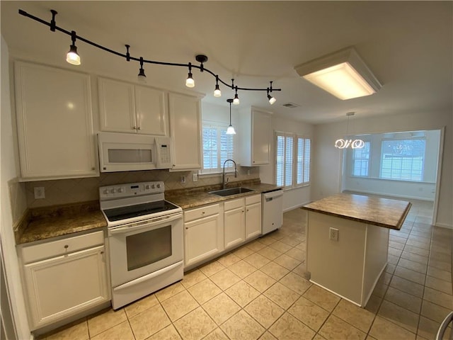 kitchen with white appliances, light tile patterned flooring, a sink, white cabinets, and tasteful backsplash