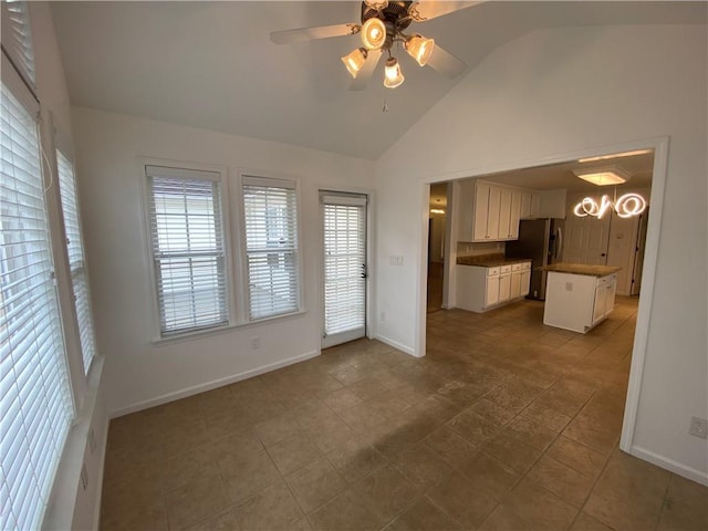 unfurnished living room with a ceiling fan, baseboards, and vaulted ceiling