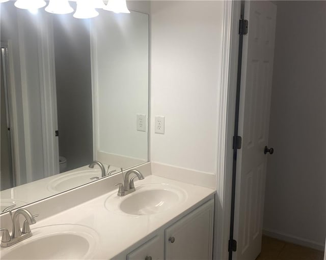 bathroom with a sink, toilet, and double vanity