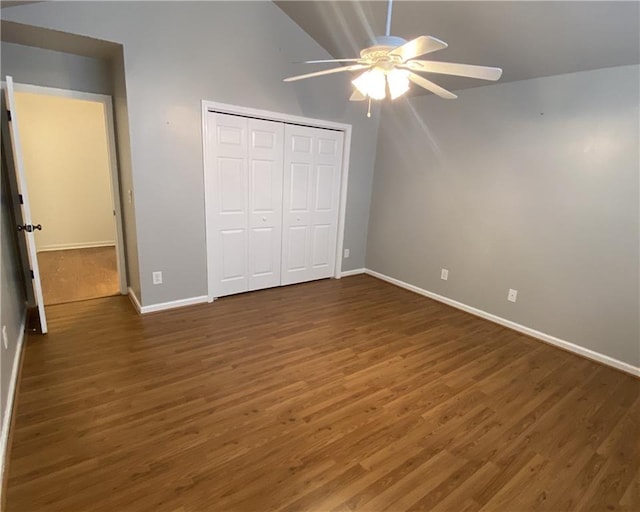 unfurnished bedroom with lofted ceiling, wood finished floors, a closet, and baseboards