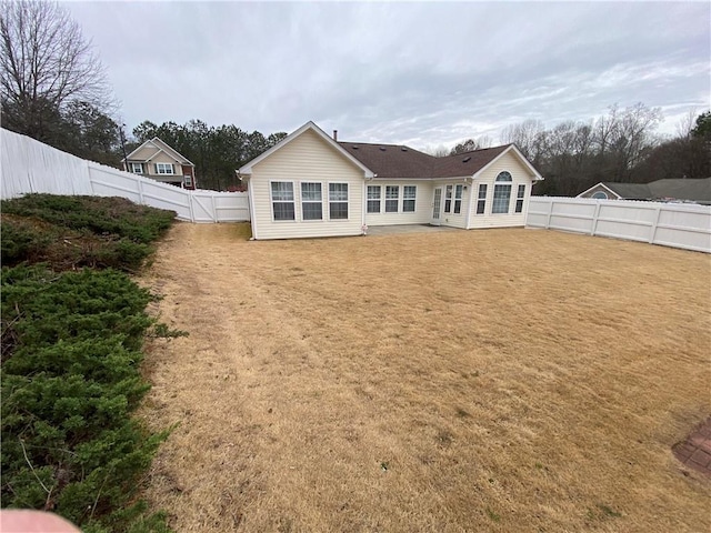 rear view of house featuring a lawn and a fenced backyard