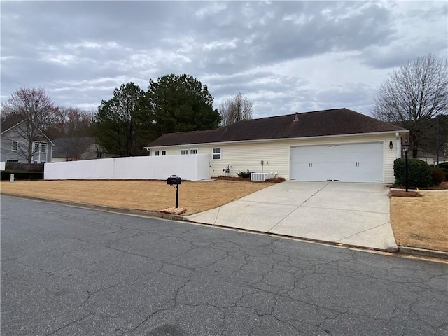 view of front of home featuring central air condition unit, fence, a garage, and driveway