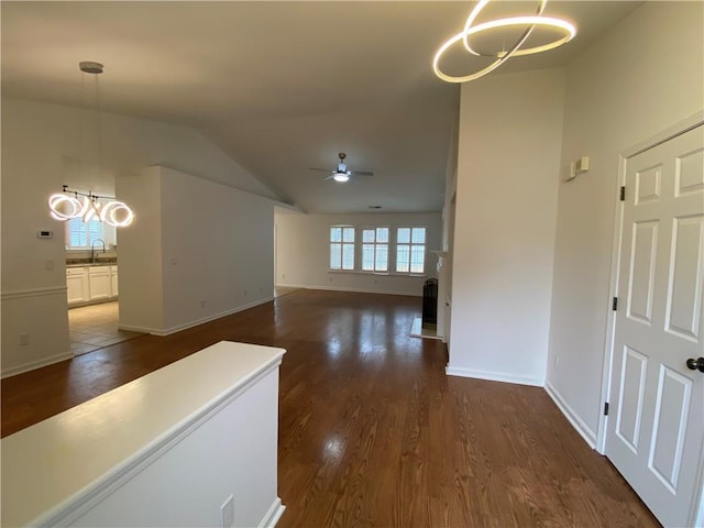 corridor featuring a wealth of natural light, a notable chandelier, and dark wood finished floors