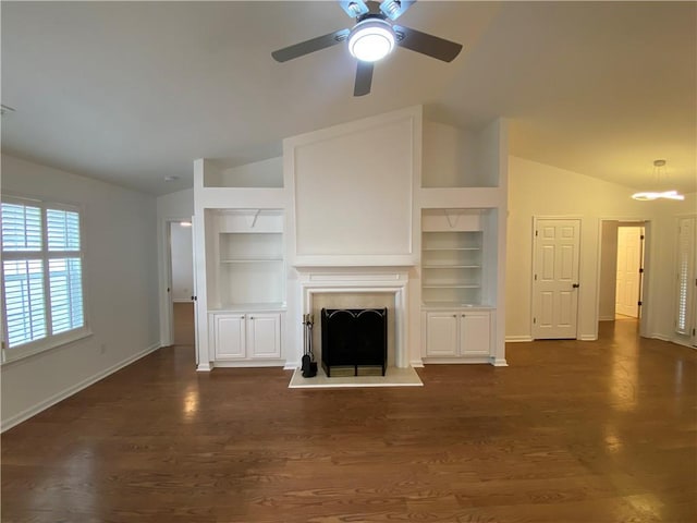 unfurnished living room featuring lofted ceiling, dark wood-style floors, and a fireplace with raised hearth