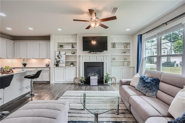 living room featuring visible vents, recessed lighting, dark wood-type flooring, and a fireplace with flush hearth