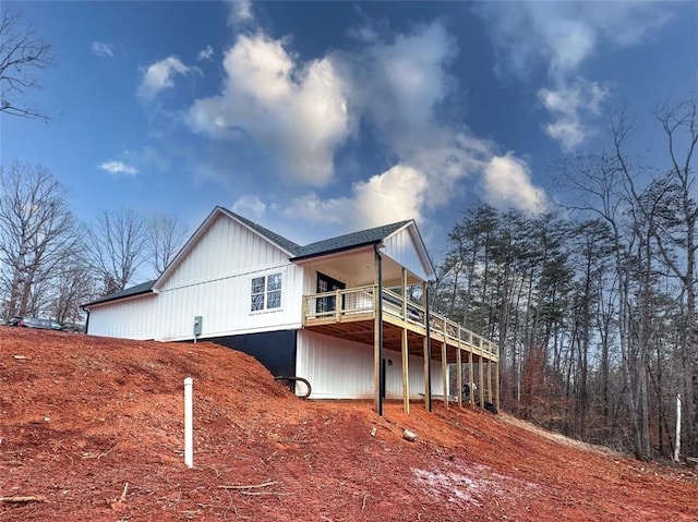 view of home's exterior featuring a shingled roof and a wooden deck