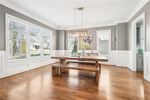 dining room with a wainscoted wall, crown molding, an inviting chandelier, and wood finished floors