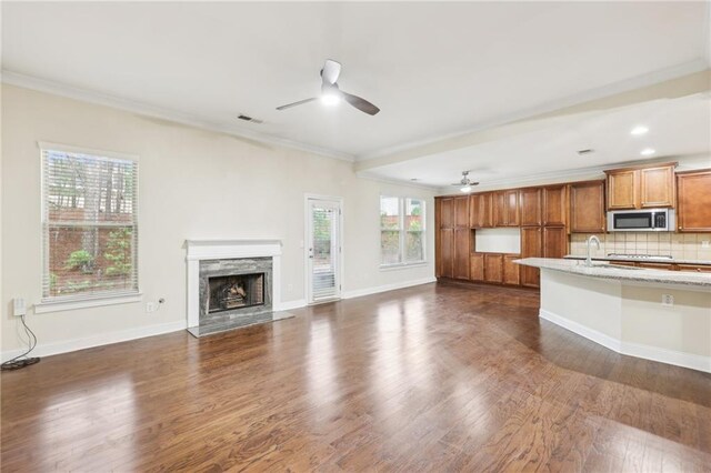 2760 Lions Gate Dr, Cumming, GA 30041 - kitchen featuring stainless steel microwave, a ceiling fan, ornamental molding, brown cabinetry, and a fireplace
