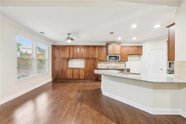 2760 Lions Gate Dr, Cumming, GA 30041 - kitchen with appliances with stainless steel finishes, a sink, brown cabinetry, ornamental molding, and dark wood-type flooring