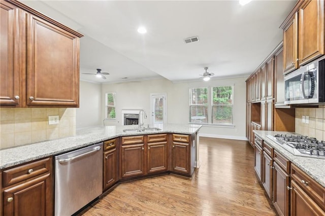 2760 Lions Gate Dr, Cumming, GA 30041 - kitchen featuring a ceiling fan, stainless steel appliances, a sink, crown molding, and light wood-style floors