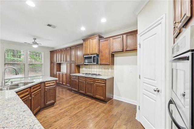 2760 Lions Gate Dr, Cumming, GA 30041 - kitchen featuring appliances with stainless steel finishes, a sink, a ceiling fan, decorative backsplash, and light stone countertops