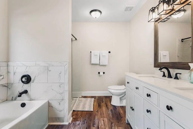 full bathroom with visible vents, toilet, a bathing tub, wood finished floors, and vanity