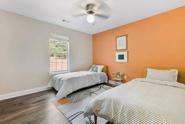 bedroom featuring ceiling fan, visible vents, baseboards, and wood finished floors