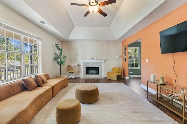 living room with visible vents, baseboards, ceiling fan, a fireplace with flush hearth, and wood finished floors