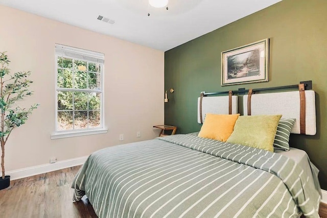 bedroom featuring wood finished floors, visible vents, and baseboards