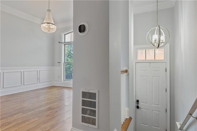 entryway featuring hardwood / wood-style flooring, a notable chandelier, and ornamental molding