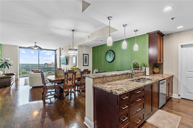 kitchen featuring pendant lighting, sink, stainless steel dishwasher, light stone counters, and kitchen peninsula