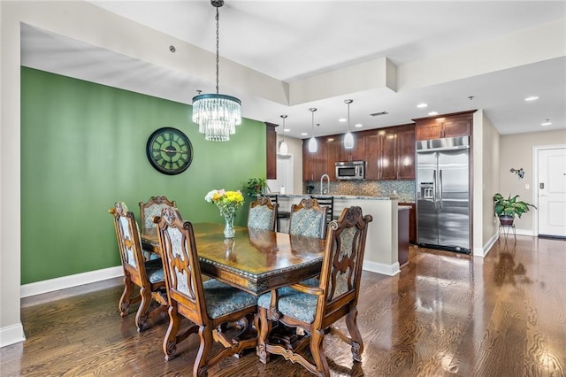 dining area with dark hardwood / wood-style floors, a chandelier, and sink