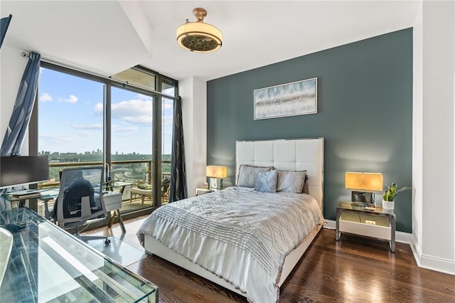 bedroom with expansive windows and dark hardwood / wood-style flooring