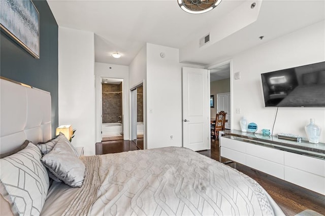 bedroom featuring dark wood-type flooring and ensuite bath