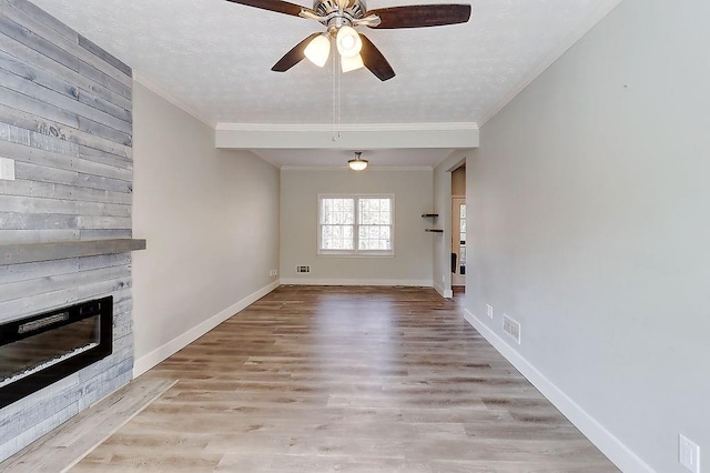 unfurnished living room with a textured ceiling, ceiling fan, light hardwood / wood-style floors, and crown molding