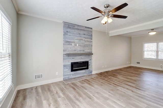 unfurnished living room featuring ceiling fan, a large fireplace, light hardwood / wood-style floors, and crown molding