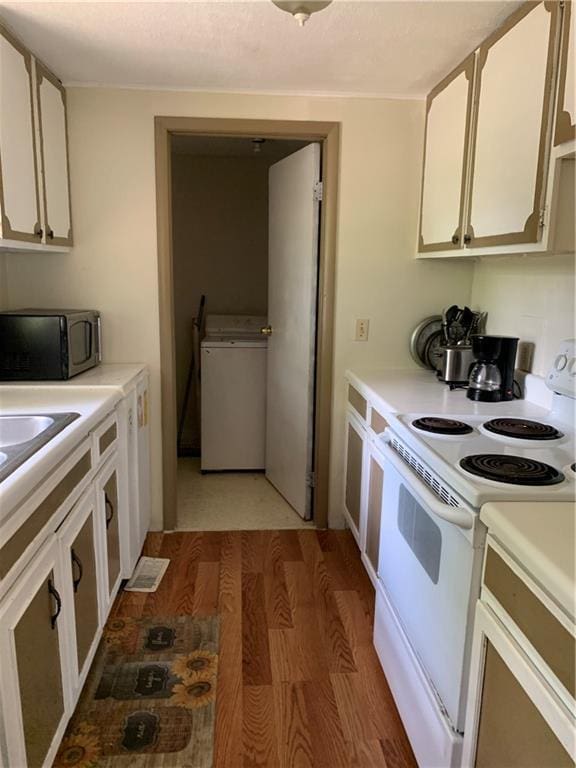 kitchen featuring light countertops, electric stove, washer / clothes dryer, white cabinetry, and light wood-type flooring