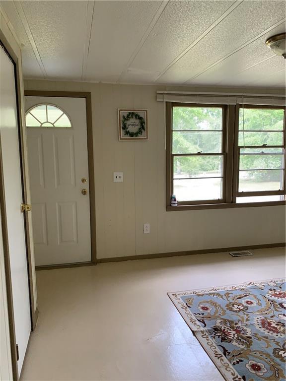 entryway with a textured ceiling, baseboards, and finished concrete flooring